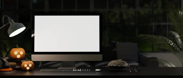 Modern dark office desk in Halloween decor with computer desktop white screen mockup, table lamp, accessories and Halloween decor stuff. 3d rendering, 3d illustration