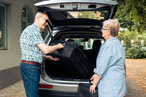 istock Aged couple putting bags in vehicle trunk 1421843799