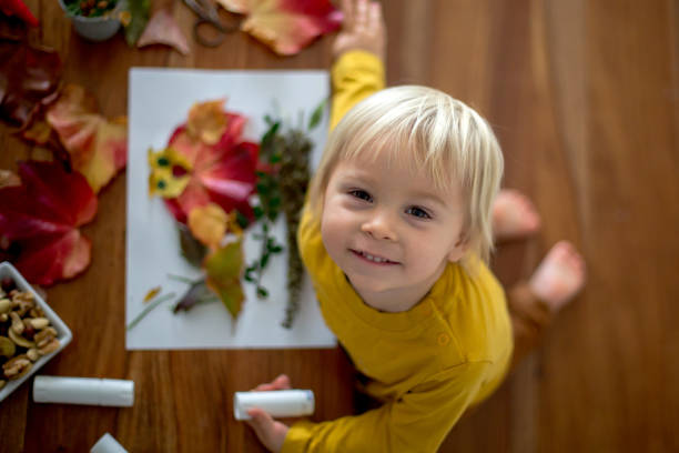 istock Sweet child, toddler boy, applying leaves using glue 1421844669