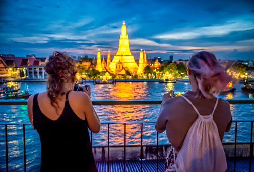Bangkok, Thailand - September 9, 2019: two Tourists womans taking photos of Wat Arun temple at night with a dslr camera and a smartphone, Bangkok. Thailand