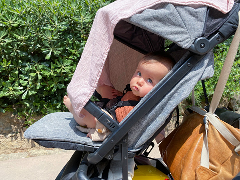 Baby daughter in a sun  protected carriage relax mode during a holiday trip in Spain