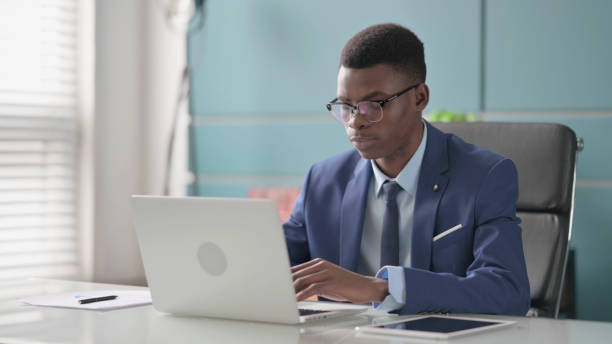 istock Young African Businessman Working on Laptop in Office 1421849147