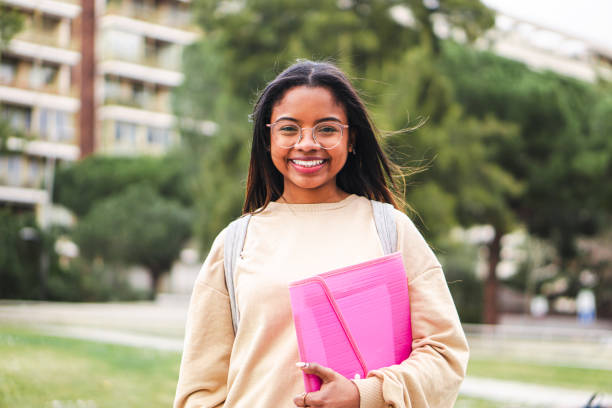 studentessa ispanica felice con gli occhiali che sorride e ride fuori dalla classe. simpatico studente adolescente in piedi nel campus universitario - spanish culture women latin american and hispanic ethnicity mexican culture foto e immagini stock