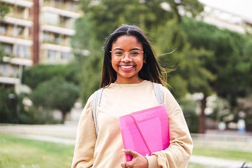 Happy hispanic school girl with glasses smiling and laughing out of class. Cute teenage student standing at the university campus. High quality 4k footage