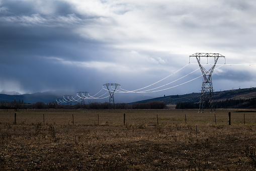 Power lines lit up by the sunlight coming through dark clouds, Central Otago, South Island.