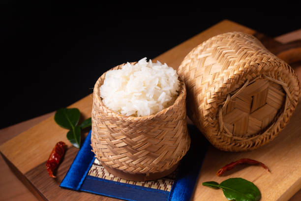 concepto de comida asiática arroz glutinoso o arroz pegajoso en mimbre de bambú sobre tabla de madera y fondo negro con espacio de copia - bamboo brown cooking gourmet fotografías e imágenes de stock