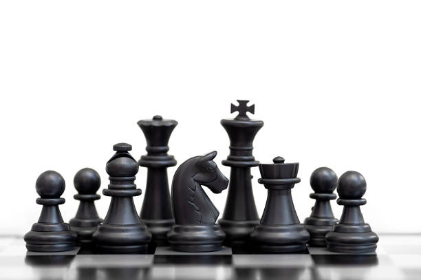 istock Black chess pieces on a chessboard stand in a row on a white background. 1421875534