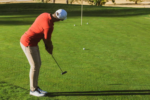 istock golfer practicing putter technique, alignment, grip and stance on the putting green at the golf driving range. Golf practices. Golf putter stroke to the hole. golfer hitting training putt in the hole 1421880329