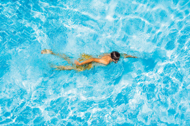istock Young man swims in the pool, summer vacation concept 1421881739