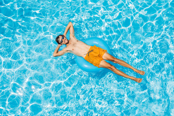 Young man swims in the pool, summer vacation concept