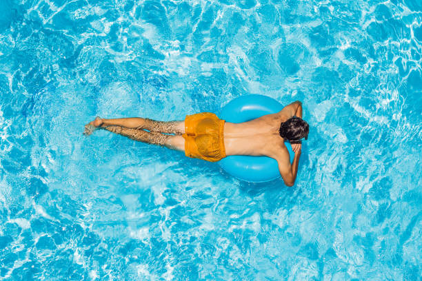 istock Young man swims in the pool, summer vacation concept 1421881762