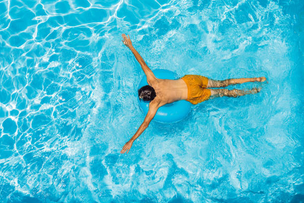 istock Young man swims in the pool, summer vacation concept 1421881765