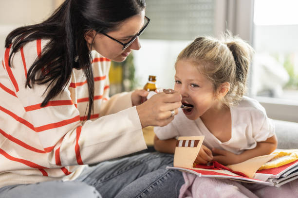 Mother giving liquid medicine to her sick daughter Close-up shot of mother giving liquid medicine to her sick daughter who having cold child liquid medicine stock pictures, royalty-free photos & images