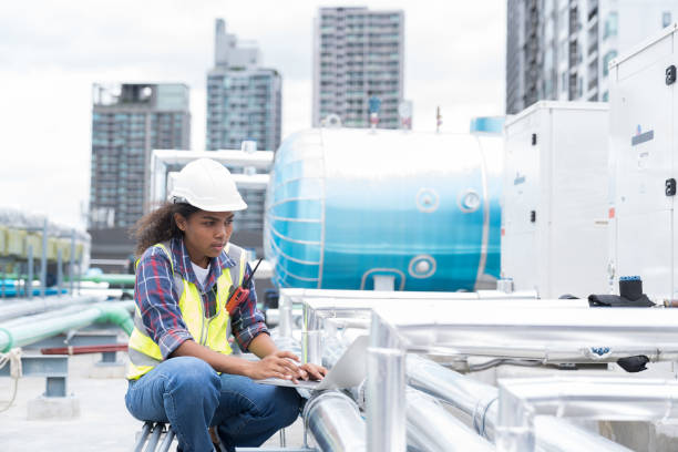 istock Female engineer working with laptop computer for maintenance in sewer pipes area at construction site. African American woman engineer working in workplace at rooftop of building 1421886703