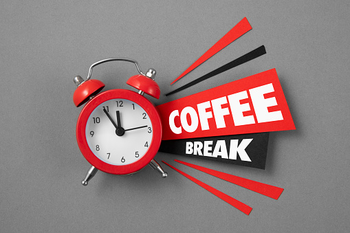 Red alarm clock with papers and coffee break message on gray background