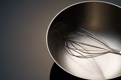 stainless whisk and bowl on dark background