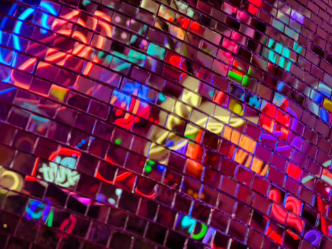 Abstract background depicting colorful neon lights reflected in a disco ball.