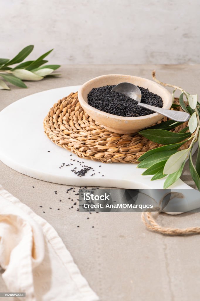 Black sesame seeds or gergelim in ceramic bowl with spoon in kitchen countertop. For healthy food and diet concepts. Top view in ceramic bowl with spoon in kitchen countertop. For healthy food and diet concepts. Breakfast Cereal Stock Photo