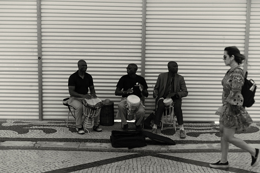 Lisbon, Portugal - July 2, 2022: A trio of african street musicians play percussion at the Rua Augusta street in Lisbon downtown.