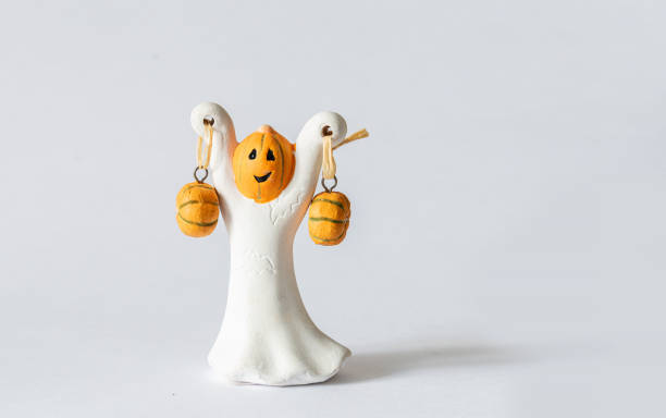 Toy ghost with pumpkins in his hands. Halloween.