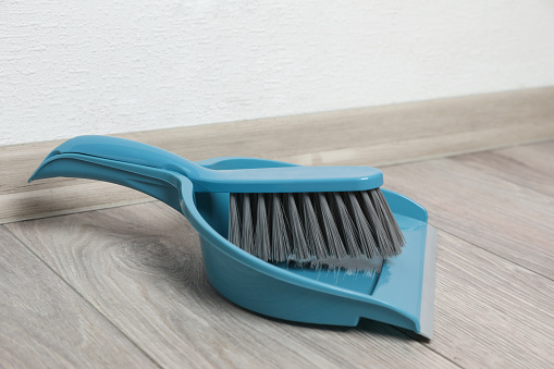 Plastic whisk broom with dustpan on wooden floor indoors