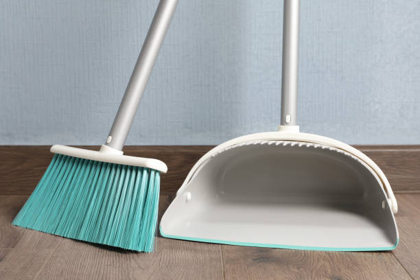 istock Plastic broom with dustpan near light blue wall indoors 1421903520