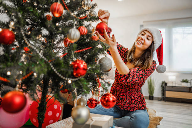 istock Young woman decorating a Christmas tree 1421903833