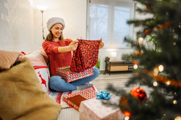 istock Woman opening Christmas present while alone at home 1421903965