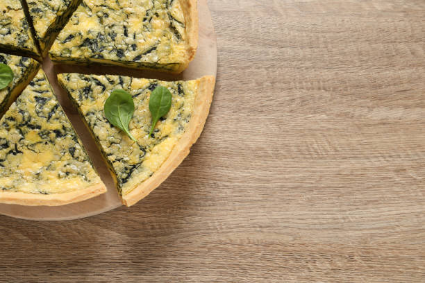 istock Cut delicious spinach pie on wooden table, top view. Space for text 1421904091