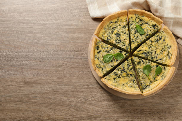 istock Cut delicious spinach pie on wooden table, top view. Space for text 1421905622