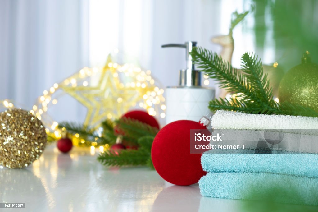 Christmas SPA Stack of blue and white towels folded on the table, fir branches, Christmas balls and Christmas lights. SPA massage or beauty salon, skin care and body care in Christmas or New Year variant. Bathroom Stock Photo