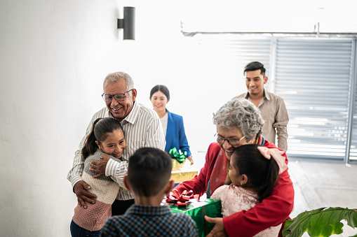 Family arriving with christmas present for children while embracing at home
