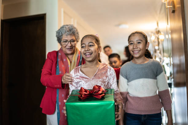 Child holding christmas present while family enters home Child holding christmas present while family enters home happy birthday cousin stock pictures, royalty-free photos & images