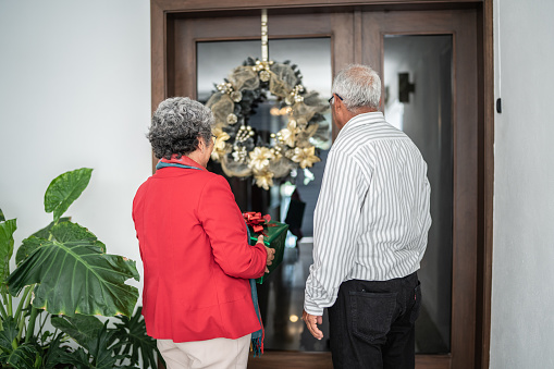 Senior couple at front door with christmas present