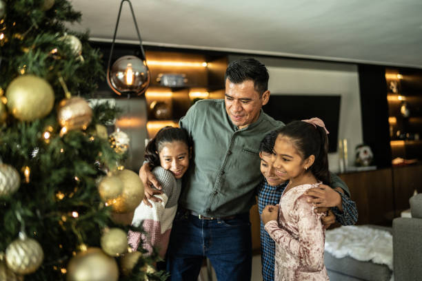 istock Father embracing his children while look christmas tree at home 1421912171