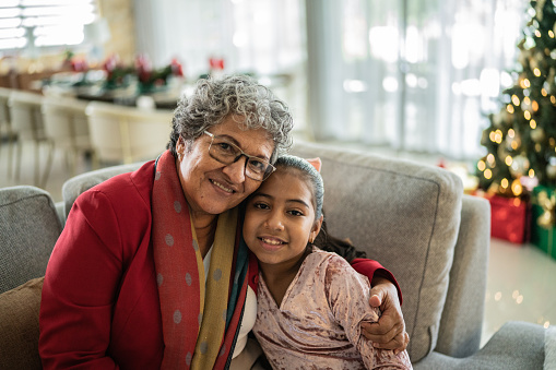Portrait of granddaughter with grandmother in the living room on the Christmas time at home