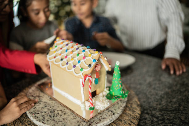 Family decorating a gingerbread house for Christmas