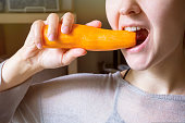 A girl chews a carrot