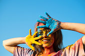 Woman covered in holi powder against blue sky. Holi colours festival.