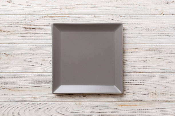 istock Top view of empty square plate on wooden background. Empty space for your design 1421925900
