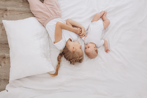 A picture of a toddler and her little sister waking up and lying in bed.