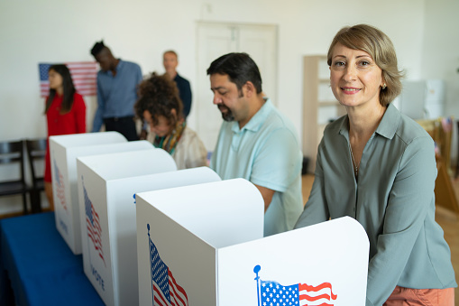 Woman smiling at the camera while voting standing in a voting booth  at the election center