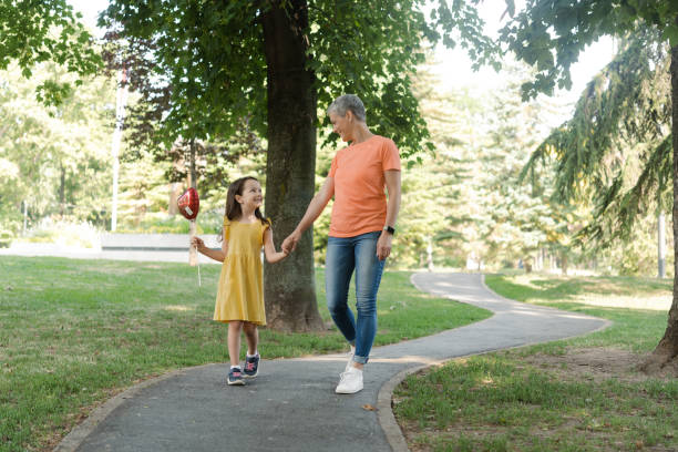 istock Cute girl with a balloon walking with her mom 1421933052