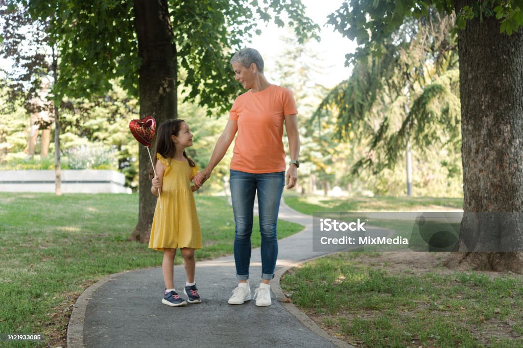 Mother and daughter walking and enjoying outdoors Portrait of a happy mother and her little daughter enjoying a walk in the park Healthy Lifestyle Stock Photo