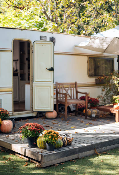 istock Caravan mobile home with terrace, Mobile home decorated with autumn decor. Cozy atmosphere - flowers, fallen leaves, pumpkins. Caravan camping. mobile home trailer. Selective focus 1421934009
