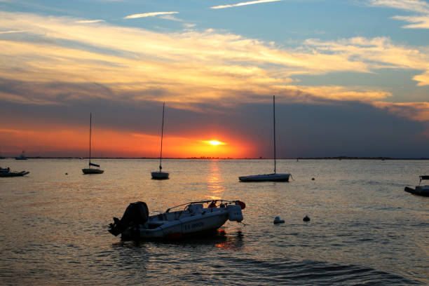 Boats moored in the foreground with the sun setting over the grreat south bay in the background taken from Fire Island National Sea Shore.