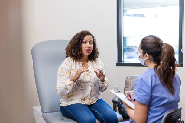 Adult patient gestures while talking to the nurse The female adult patient talks to the nurse about symptoms she has been experiencing. womens issues stock pictures, royalty-free photos & images