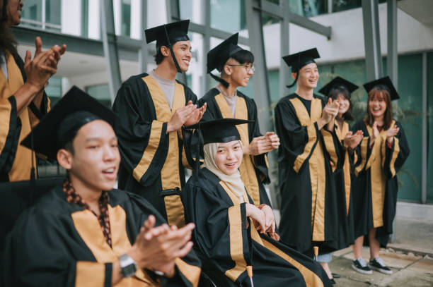 istock Asian diversify students in graduation gown clapping hands cheering for classmate during graduation ceremony outdoor 1421945247