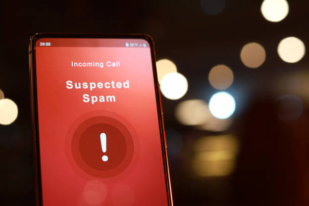 Suspected spam call from an unknown caller shown a smartphone display screen against illuminated light background stock photo