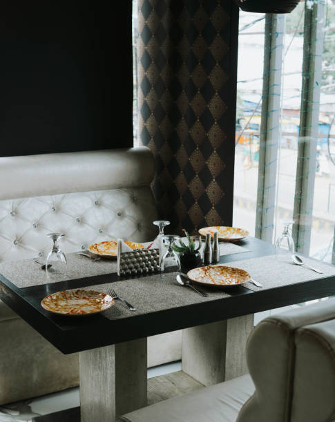 Window Illuminated Restaurant table with cluttered plates & Flipped wine glasses